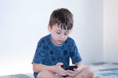 Beyaz bir geçmişi olan akıllı telefon kullanan genç bir çocuk.