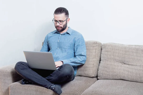 Evde çalışan genç bir adamın fotoğrafı. Bir vagonda oturuyor ve mavi gömlek giyiyor.