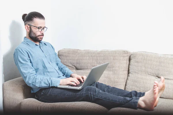 Evde çalışan genç bir adamın fotoğrafı. Bir vagonda oturuyor ve mavi gömlek giyiyor.