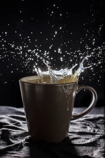 Coffee drop with smoke in the brown glass black background