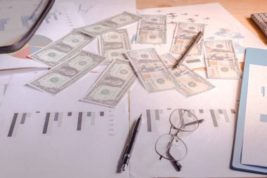 Planın arkasındaki masada masanın üzerinde grafikler, kalemler ve bardaklar vardı..