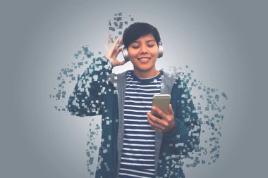  Asyalı genç adam mutlu ve gülümsüyor. Cep telefonundan müzik dinliyor. Gri arka planda piksellere karışıyor.