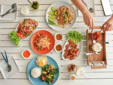 Tavuklu pilav, yumurta, sebze, papaya salatası kızarmış tavuk ve kızarmış kale, beyaz ahşap masada Tayland domuz salatası.