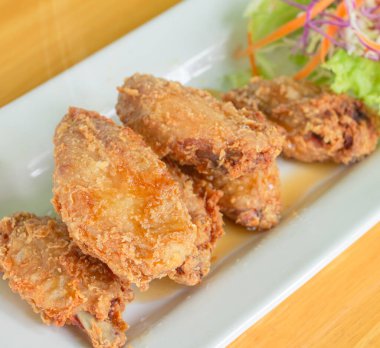 Kızarmış tavuk, balık sosu, marul, havuç, karnabahar, ahşap bir masada beyaz bir tabakta kayın.