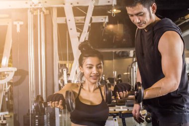 Spor salonundaki genç Asyalı kadın kişisel antrenör, günbatımına yakın spor konsepti olan halter, spor salonu yetiştirildi..