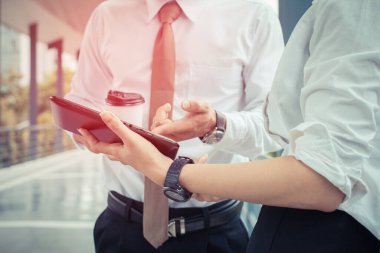 İş adamı ve kadının elinde telefon, dışarıda sıcak kahve, günbatımına odaklan.