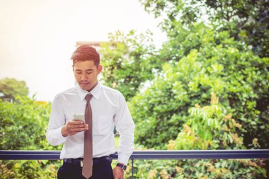 .Cep telefonu sohbeti yapan Asyalı genç işadamı, bir ürün veya hizmetin tanıtımı ve satışı ve dağıtımı ile ilgili ticari süreçleri selamlıyor