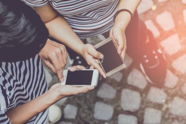 Erkek ve kadının ellerinin cep telefonuna dokunduğu ve yolda hafif günbatımı, klasik tonlu mesajınız için boş fotokopi alanı olan el kameralarını kapatın.