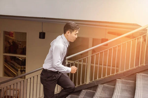 若いアジアのビジネスマンが階段を駆け上がり オフィスサービスに駆けつける屋外 光の日没の背景 — ストック写真