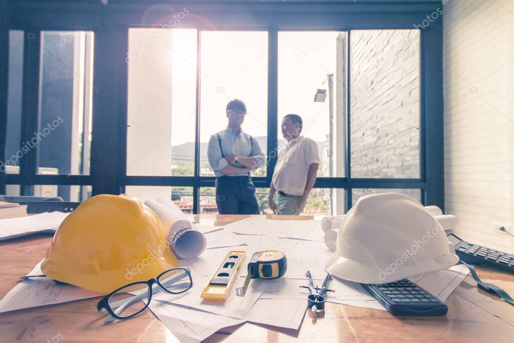 Concept architects, equipment architects ,On the desk with a blueprint in the office,Man are standing meeting. Vintage, Sunset ligth.Selective Focus