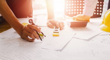  Mimari projeler bürosu planlarla çalışıyor. Seçmeli odak noktası. Günbatımı arkaplanlı klasik ton..