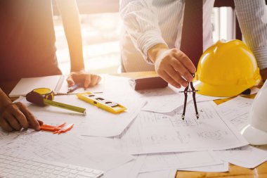  Mimari projeler bürosu planlarla çalışıyor. Seçmeli odak noktası. Günbatımı arkaplanlı klasik ton..