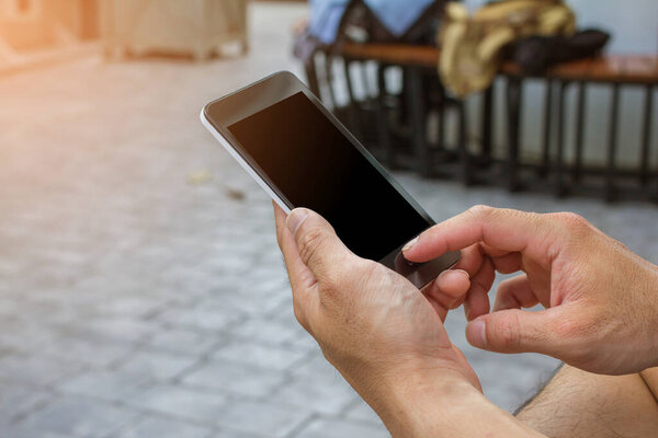 Close up of men hands holding touching mobile phone with blank copy space for your text message at park with light Sunset,Vintage tone.Selective focus