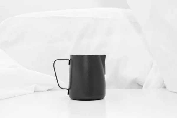 Black milk stainless pitcher object make coffee on white table and fabric background