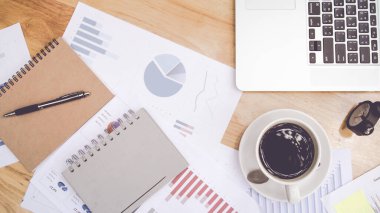 Dizüstü bilgisayarı, malzemesi ve sıcak kahvesi olan en iyi ofis masası, grafik kağıdı. Metin için kopyalama alanı