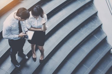 İş adamı ve kadın tablet kullanıyor. Reklamdaki ticari faaliyetlerle buluşuyor. Birlikte merdivenlerde karşılıklı fayda sağlayacağız. Dışarıda.