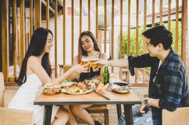 İki Asyalı kadın ve bir erkek. Bira içiyorum. Grup kutlama partisi mutlu yemek, konsept  