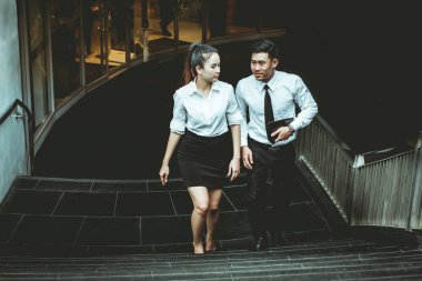 İş adamı ve kadın çalışmaktan bahsediyor. Reklamdaki ticari faaliyetlerle buluşuyor. Birlikte merdivenlerde karşılıklı fayda sağlayacağız. Dışarıda. 