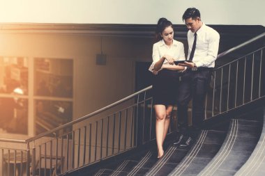 İş adamı ve kadın tablet kullanıyor. Reklamdaki ticari faaliyetlerle buluşuyor. Birlikte merdivenlerde karşılıklı fayda sağlayın. Dışarıda. Klasik ton.