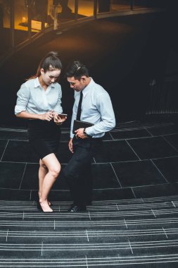 İş adamı ve kadın cep telefonu kullanıyor. Reklamdaki ticari faaliyetlerle buluşuyor. Birlikte merdivenlerde karşılıklı fayda sağlayacağız. Dışarıda. 