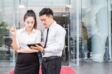 İş adamı ve kadın tablet kullanıyor. Tanıtım toplantıları. Karı eşit olarak paylaşacaklarına dair karşılıklı bir anlaşma yapmışlardı. Dışarıda.