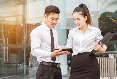 İş adamı ve kadın tablet kullanıyor. Tanıtım toplantıları. Karı eşit olarak paylaşacaklarına dair karşılıklı bir anlaşma yapmışlardı. Dışarıda.