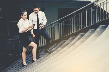 İş adamı ve kadın tablet kullanıyor. Reklamdaki ticari faaliyetlerle buluşuyor. Birlikte merdivenlerde karşılıklı fayda sağlayacağız. Dışarıda.