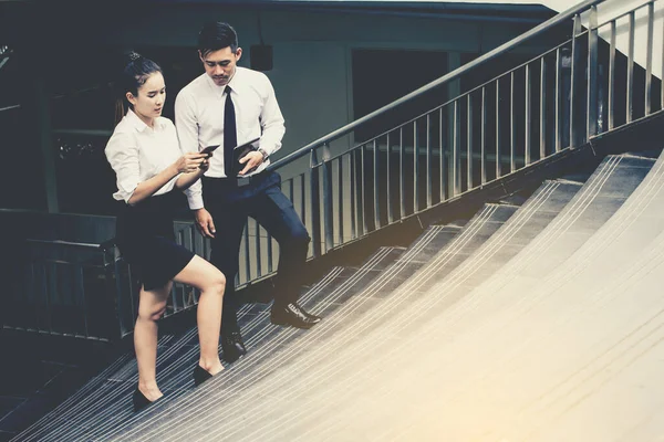 İş adamı ve kadın tablet kullanıyor. Reklamdaki ticari faaliyetlerle buluşuyor. Birlikte merdivenlerde karşılıklı fayda sağlayacağız. Dışarıda.