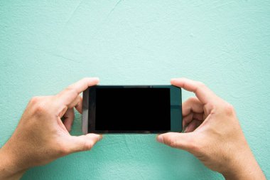 Açık Günbatımı, Vintage tonlu yeşil arkaplan üzerindeki mesajınız için boş kopya alanı olan oyun cep telefonuna dokunan erkeklerin ellerini kapat. Seçici odak noktası