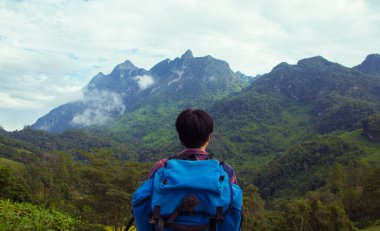 İskoç gömlekli ve siyah şapkalı Asyalı genç bulutların tepesinde dağ yürüyüşü ve dışarıda sis Hiker. Doi Luang Chiang Dao Chiangmai Eyaleti, Sabah.