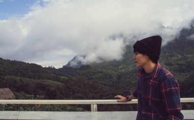 İskoç gömlekli ve siyah şapkalı Asyalı genç bulutların tepesinde dağ yürüyüşü ve dışarıda sis Hiker. Doi Luang Chiang Dao Chiangmai Eyaleti, Sabah.