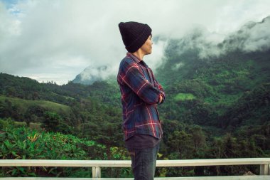 İskoç gömlekli ve siyah şapkalı Asyalı genç bulutların tepesinde dağ yürüyüşü ve dışarıda sis Hiker. Doi Luang Chiang Dao Chiangmai Eyaleti, Sabah.