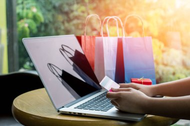 Kapat şunu, genç Asyalı kadın dizüstü bilgisayarda klavye yazıyor ve elinde internet alışverişi veya internet bankacılığı kavramı olan bir kahve dükkanında kredi kartı tutuyor.