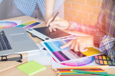 Tasarımcı grafik yaratıcı, elinde kalem tutan adam ofiste dizüstü bilgisayarla çalışıyor günbatımı arka planı, seçici odaklanma.