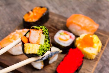 Üst Manzara, Sushi Sashimi ve suşi ruloları ahşap levhada servis edilir. Metnin için alanı kopyala.