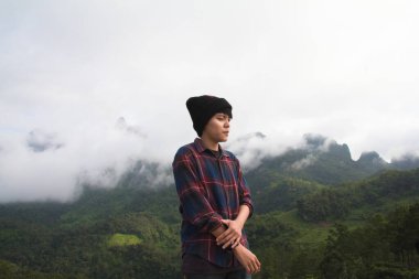 İskoç gömlekli ve siyah şapkalı Asyalı genç bulutların tepesinde dağ yürüyüşü ve dışarıda sis Hiker. Doi Luang Chiang Dao Chiangmai Eyaleti, Sabah.