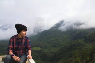 İskoç gömlekli ve siyah şapkalı Asyalı genç bulutların tepesinde dağ yürüyüşü ve dışarıda sis Hiker. Doi Luang Chiang Dao Chiangmai Eyaleti, Sabah.