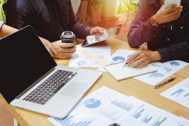 İş adamı cep telefonu ve kalem yazma raporunu kullanarak ekonomideki grafiği ve düşüşü tartışıyor..