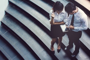İş adamı ve kadın tablet kullanıyor. Reklamdaki ticari faaliyetlerle buluşuyor. Birlikte merdivenlerde karşılıklı fayda sağlayacağız. Dışarıda.