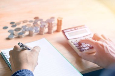 Mavi gömlekli bir iş adamı. Elinde kalem yazısı, hesap makinesi ve mali veri hesaplaması. Tahta masadaki hesap makinesini analiz ediyor ve sayıyor..