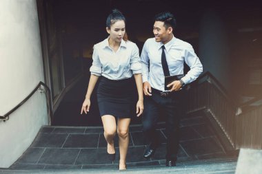 Asian businessman and businesswoman or Confident business partners walking  up on staircase office building and talking ,Corporate Level Strategy Growth Strategy Conglomerate Diversification.