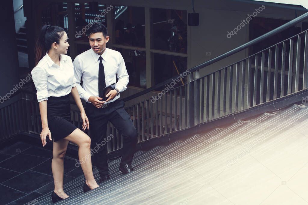 Asian businessman and businesswoman or Confident business partners walking  up on staircase office building and talking ,Corporate Level Strategy Growth Strategy Conglomerate Diversification.