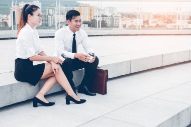 Asyalı işadamı ve iş kadını ya da merdiven ofis binasında oturan ve Kurumsal Düzey Büyüme Stratejisi Stratejisi Holdingi Çeşitliliğinden bahseden özgüvenli iş ortakları. Dinlenme zamanı.