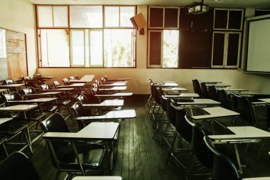 Arka planda sınıf yok, öğrenci ya da öğretmen yok. Pencerenin yanında günbatımı ışıklarıyla.