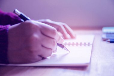 Kadın sağ el yazısı sabah evde defter üzerine güneş ışığı ve klasik tonuyla.