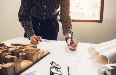 Konsept mimarlar, elinde kalem tutan mühendis ve sunum projektörleri ofiste bir planla birlikte masanın üzerinde, Vintage, Sunset Light. Seçici Odaklanma