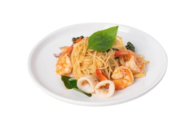 Ev aşçısı Tayland usulü karides fesleğenli baharatlı deniz ürünleri spagettisi hazırlar, beyaz arka planda servis edilen kaffir limon yaprakları, taze ev yapımı füzyon yemeği..