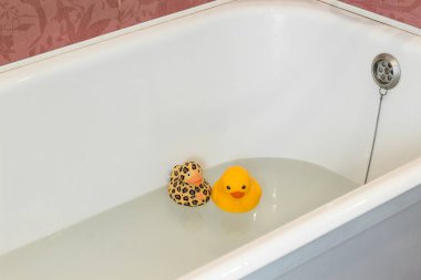 Banyoda iki lastik sarı ördek var. Çocuk için banyo, bebeği yıkamak için hazırlık. Yüzmek için oyuncaklar. Pembe fayans.