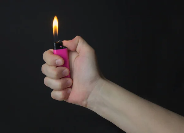 一个女人的手拿着一个粉色打火机来自打火机的燃烧的火焰 黑色背景 — 图库照片