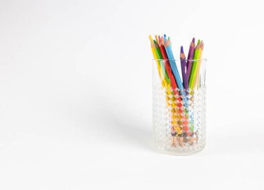 Kesimli bir bardağa çizim yapmak için renkli kalemler. Beyaz arka plan. Asimetrik bileşim. Masaüstü ekran koruyucu.